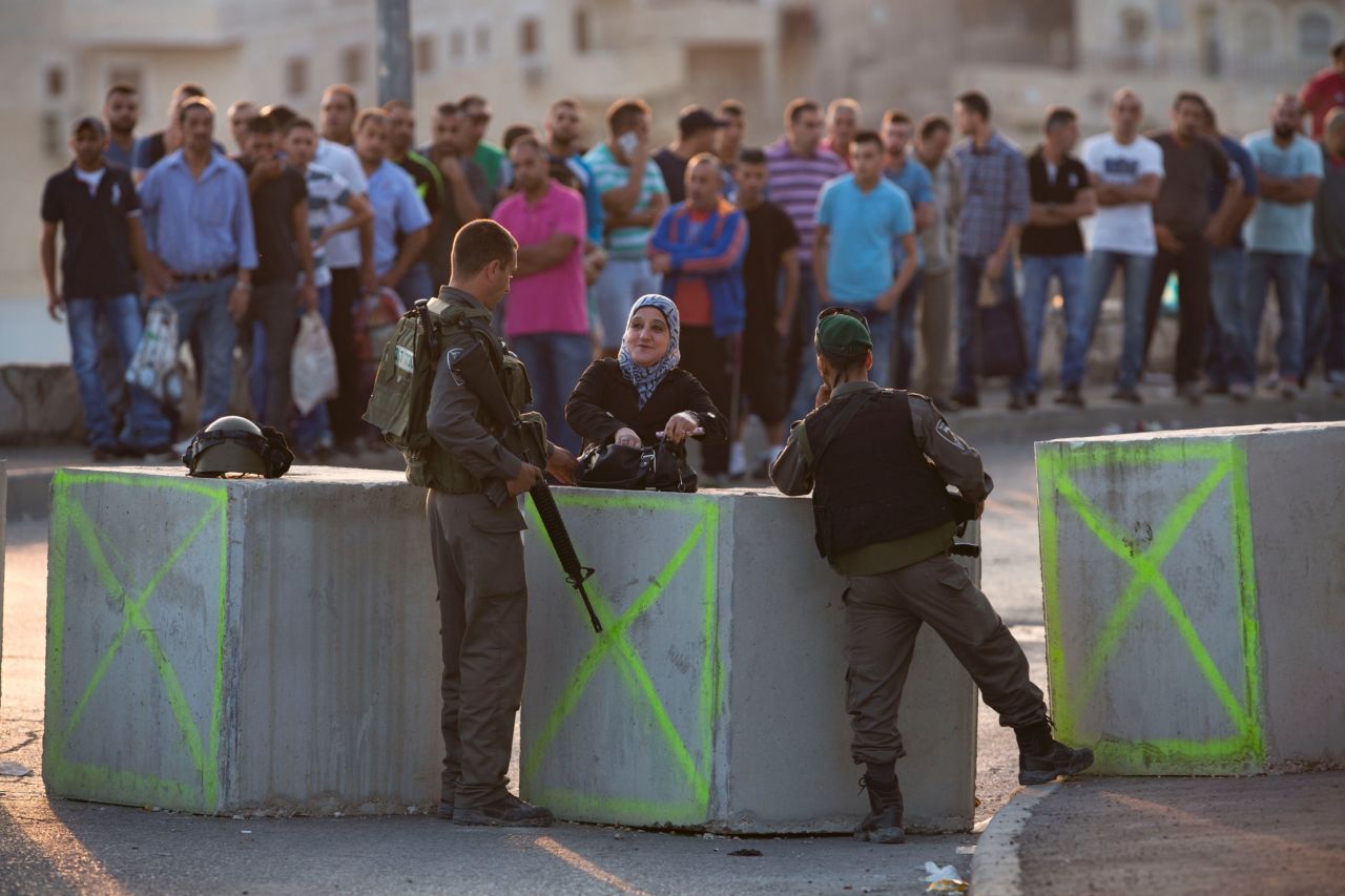 Israeli border police check  Palestinians' identification on October 18 at a checkpoint as they exit the Arab neighborhood of Issawiyeh in Jerusalem.