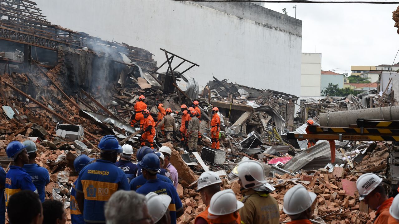 Firefighter rescue teams search for victims after an explosion swept two restaurants and a pharmacy in a suburban neighbourhood of Rio de Janeiro, on October 19, 2015. A powerful explosion suspected to be caused by illegally stockpiled gas canisters ripped through a Rio de Janeiro neighbourhood Monday, injuring at least seven people and destroying homes and businesses. Footage on Globo television from the Sao Cristovao area of northern Rio, in a neighborhood near the giant Maracana stadium, showed firefighters dousing flames and clawing through piles of twisted metal and rubble searching for survivors.  AFP PHOTO / VANDERLEI ALMEIDA        (Photo credit should read VANDERLEI ALMEIDA/AFP/Getty Images)