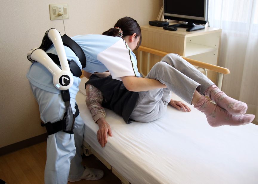 A care worker lifts a patient at the Fuyoen nursing home for elderly people. She's wearing Cyberdyne's Hybrid Assistive Limb (HAL) robot suit during a demonstration on June 12, 2015. The HAL learns its users motions and provides stability and strength.
