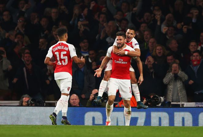 Olivier Giroud of Arsenal (C) celebrates with Alex Oxlade-Chamberlain (15) and Alexis Sanchez as he scores their first goal during the UEFA Champions League Group F match between Arsenal FC and FC Bayern Munchen at Emirates Stadium.
