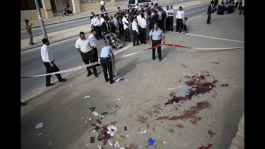 Israeli police inspect the scene of a stabbing attack in Beit Shemesh, Israel, on Thursday, October 22. Two Palestinian men armed with knives tried to board a bus carrying children but were forced back by people inside the vehicle, police said. The two men were shot by police after they stabbed an Israeli man at a bus stop.