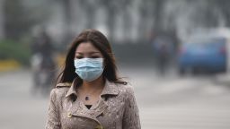 To go with China-environment-pollution-health-economy,FOCUS by Neil CONNOR
This photo taken on October 20, 2014 shows a woman wearing a mask on a heavily polluted day in Beijing. The soaring, grimy chimneys of the coal-fired power station have belched the last of their choking fumes into Beijing's air, authorities say -- but experts doubt the plan will ease the capital's smog.  AFP PHOTO/Greg BAKER        (Photo credit should read GREG BAKER/AFP/Getty Images)