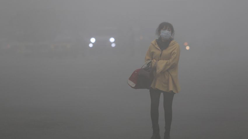A woman wearing a face mask walks in heavy smog in Harbin, northeast China's Heilongjiang province, on October 21, 2013. Choking clouds of pollution blanketed Harbin, a Chinese city famed for its annual ice festival on October 21, reports said, cutting visibility to 10 metres (33 feet) and underscoring the nation's environmental challenges.   CHINA OUT     AFP PHOTO        (Photo credit should read STR/AFP/Getty Images)