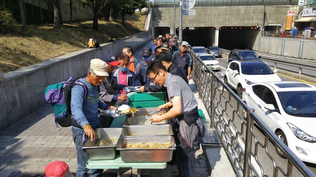 People line up to receive food from Pastor Choi Seong-Won's mobile soup kitchen.