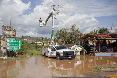 Men work to restore downed power lines on October 24 in Melaque.