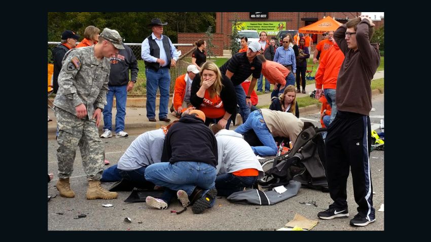 Bystanders help the injured after a vehicle crashed into a crowd of spectators during the Oklahoma State University homecoming parade, causing multiple injuries, on Saturday, Oct. 24, 2015 in Stillwater, Oka.  (David Bitton/The News Press via AP) MANDATORY CREDIT  