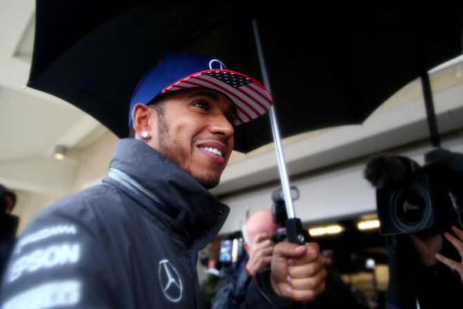 Hamilton shelters under an umbrella at the rain-hit United States Formula One Grand Prix.