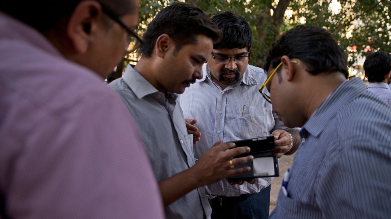 People in New Delhi look for news of the earthquake on their phones.
