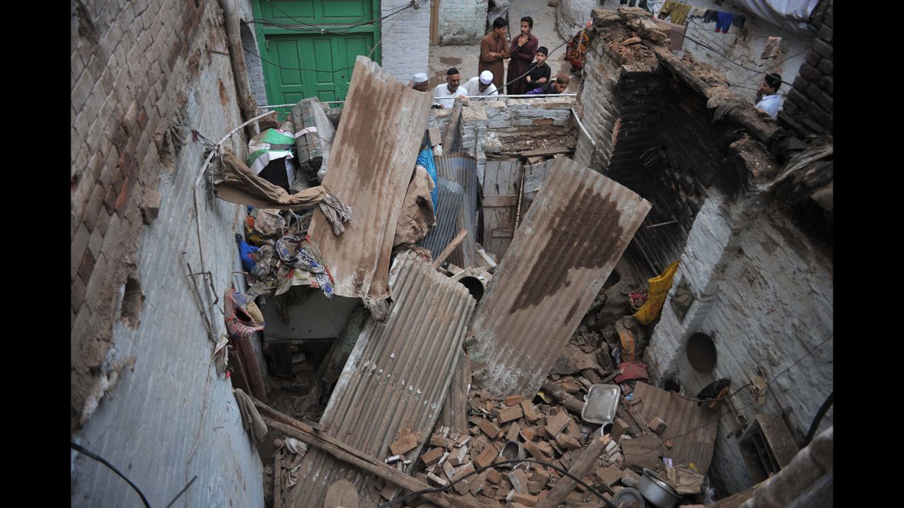 People look at a damaged house in Peshawar.