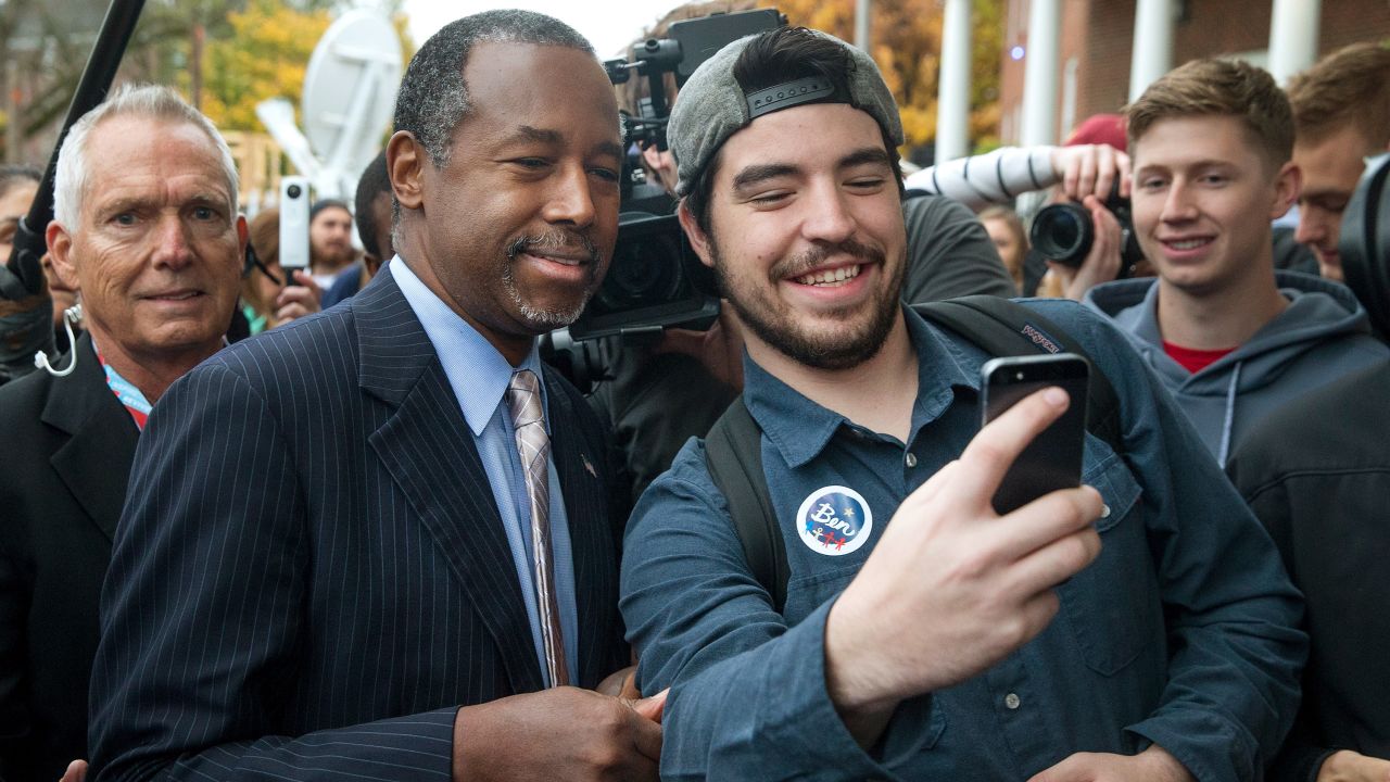 Republican presidential candidate Ben Carson, left, take a selfie outside the Alpha Gamma Rho house during a campaign stop at Iowa State University on Saturday, October 24.
