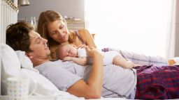 Stock Photo:Family In Bed Holding Sleeping Newborn Baby Daughter