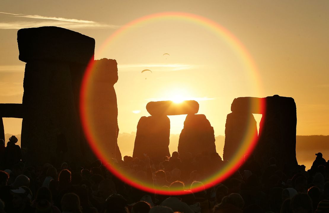 People watch the midsummer sun as it rises over the megalithic monument of Stonehenge.