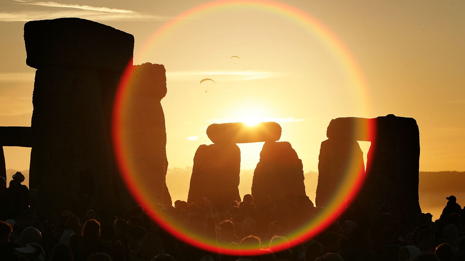  People watch the midsummer sun as it rises over Stonehenge