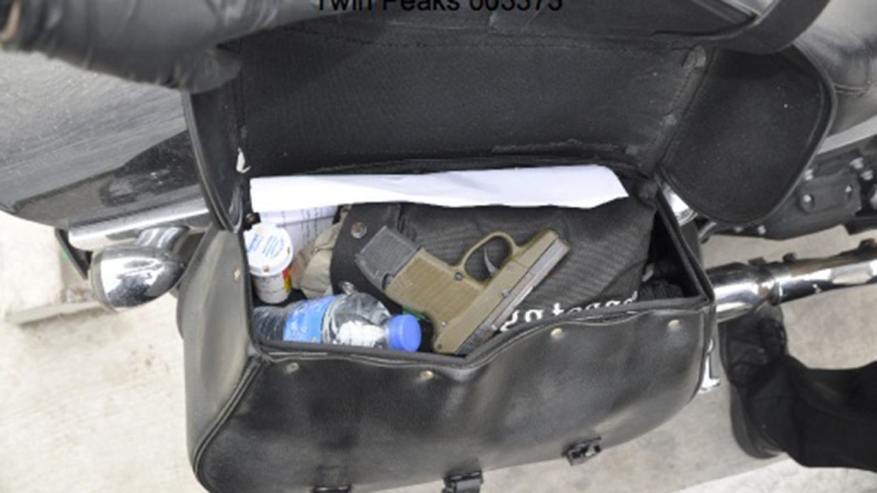 A gun is inside a motorcycle saddlebag, along with prescription medicine and a water bottle.