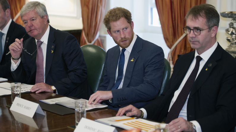 Prince Harry, flanked by Invictus Chairman Sir Keith Mills, left, and Managing Director Dominic Reid, attend an Invictus board meeting at the British Ambassador's Residence in Washington. 
