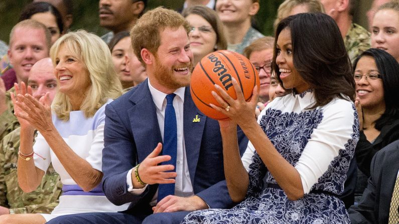 First lady Michelle Obama, accompanied by Jill Biden, left, reacts as Prince Harry hands her the basketball as the conclusion of a game of wheelchair basketball by wounded servicemen and veterans at Fort Belvoir military base. 