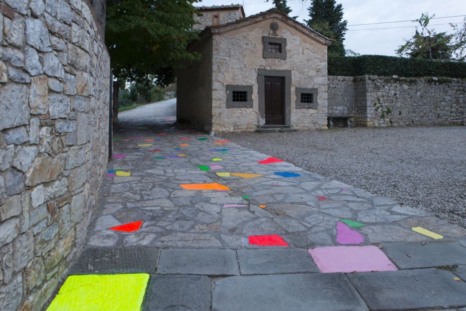 His installation at Castello di Ama is "Le Chemin du Bonheur." It features splashes of color painted on a path leading to the winery, and is intended to <a href="http://www.castellodiama.com/en/installazioni-permanenti/pascale-marthine-tayou/" target="_blank" target="_blank">encourage</a> the nostalgia of past friendships and memories. 