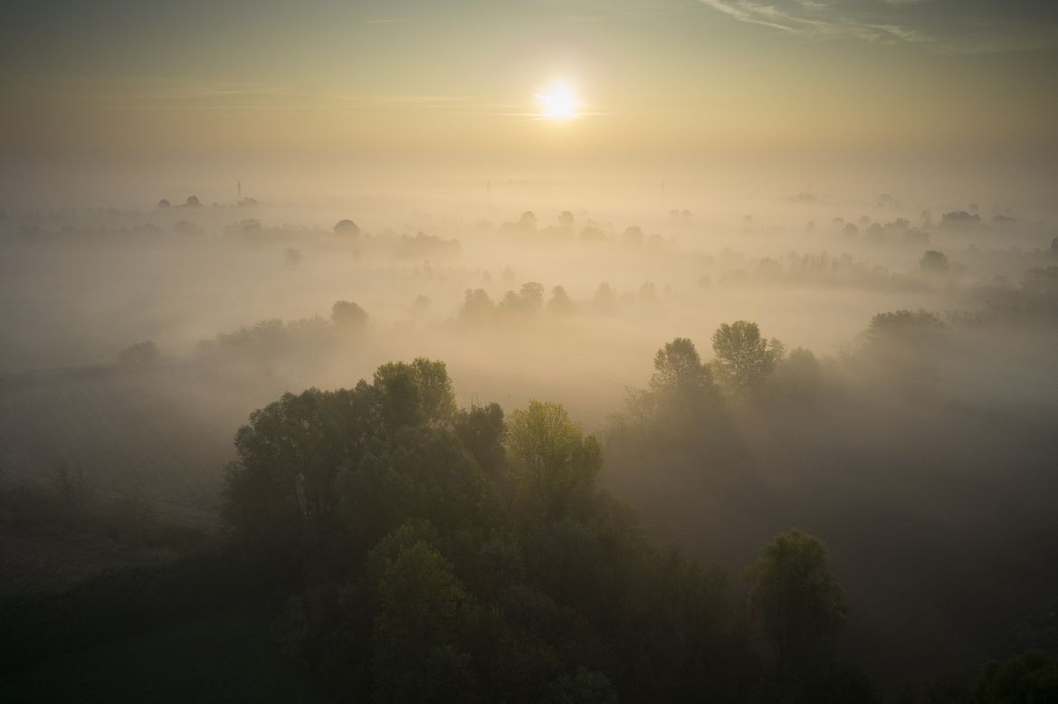 An aerial view of the sun rising above early morning mist in the countryside near Abbiategrasso, southwest of Milan on October 24.