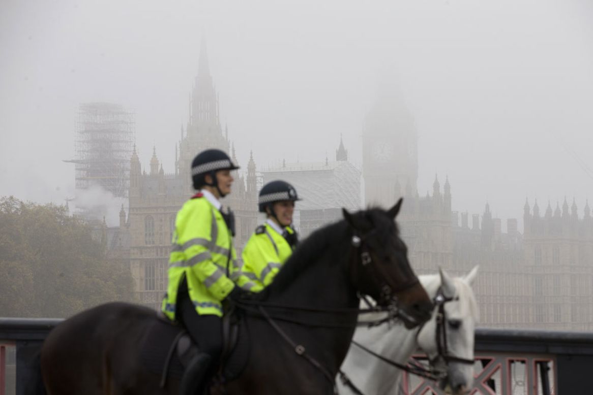 Police officers on horses ride past the Houses of Parliament in thick fog in central London on November 2.