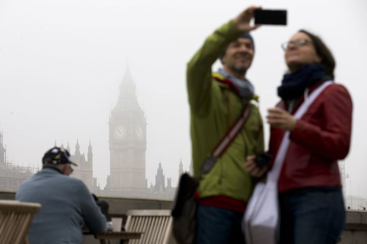 A couple take a "selfie" in front of the Houses of Parliament in central London on November 2, 2015.