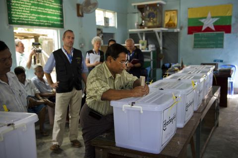 A voter casts an early ballot at a polling center in Yangon on October 30, 2015 while European Union election observers look on during a 10-day, nationwide advance voting period.