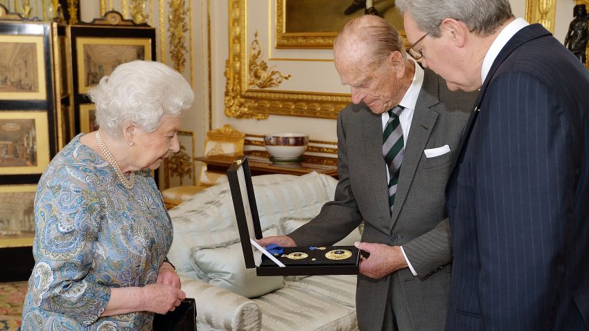 Britain's Queen Elizabeth II (L) presents Britain's Prince Philip, Duke of Edinburgh (C) with the Insignia of a Knight of the Order of Australia as Australian High Commissioner Alexander Downer (R) looks on in the white drawing room at Windsor Castle, west of London, on April 22, 2015.  Queen Elizabeth II presented her husband Prince Philip with an insignia of his Australian knighthood, the awarding of which plunged Prime Minister Tony Abbott into crisis earlier this year.