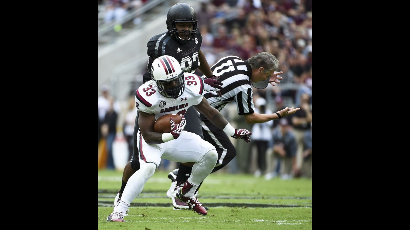 An official is knocked down as South Carolina running back David Williams scampers past Texas A&M defender Alonzo Williams during a game in College Station, Texas, on Saturday, October 31.