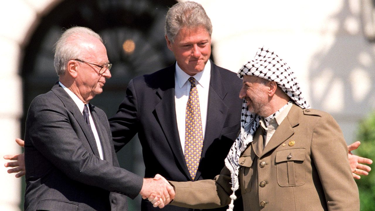 U.S. President Bill Clinton stands between Israeli Prime Minister Yitzhak Rabin, left, and PLO Chairman Yasser Arafat as they shake hands on September 13, 1993. 