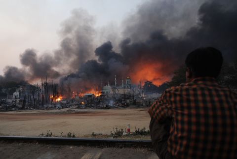 A resident watches as black smoke rises from burning houses  in riot-hit Meiktila, central Myanmar on March 21, 2013.  At least 10 people were killed in riots in central Myanmar.