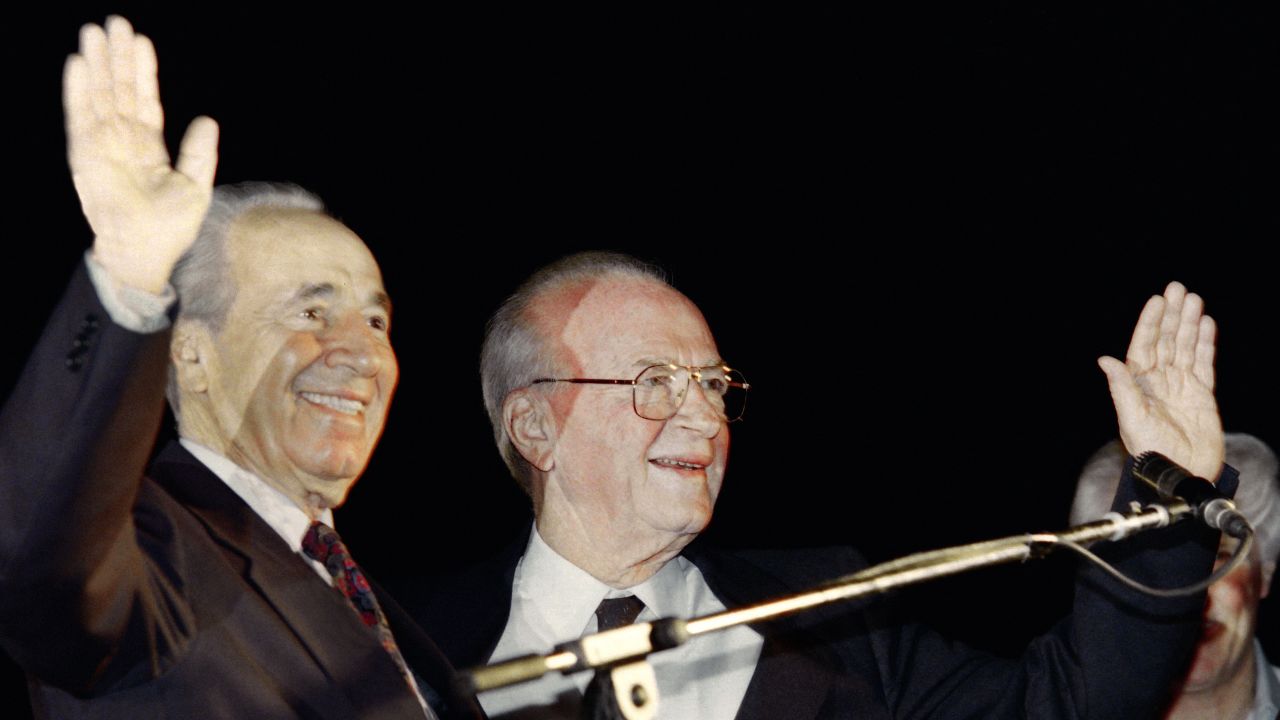 Israeli Foreign Minister Shimon Peres, left, and Prime Minister Yitzhak Rabin wave to the crowd at the peace rally in Tel Aviv on November 4, 1995.