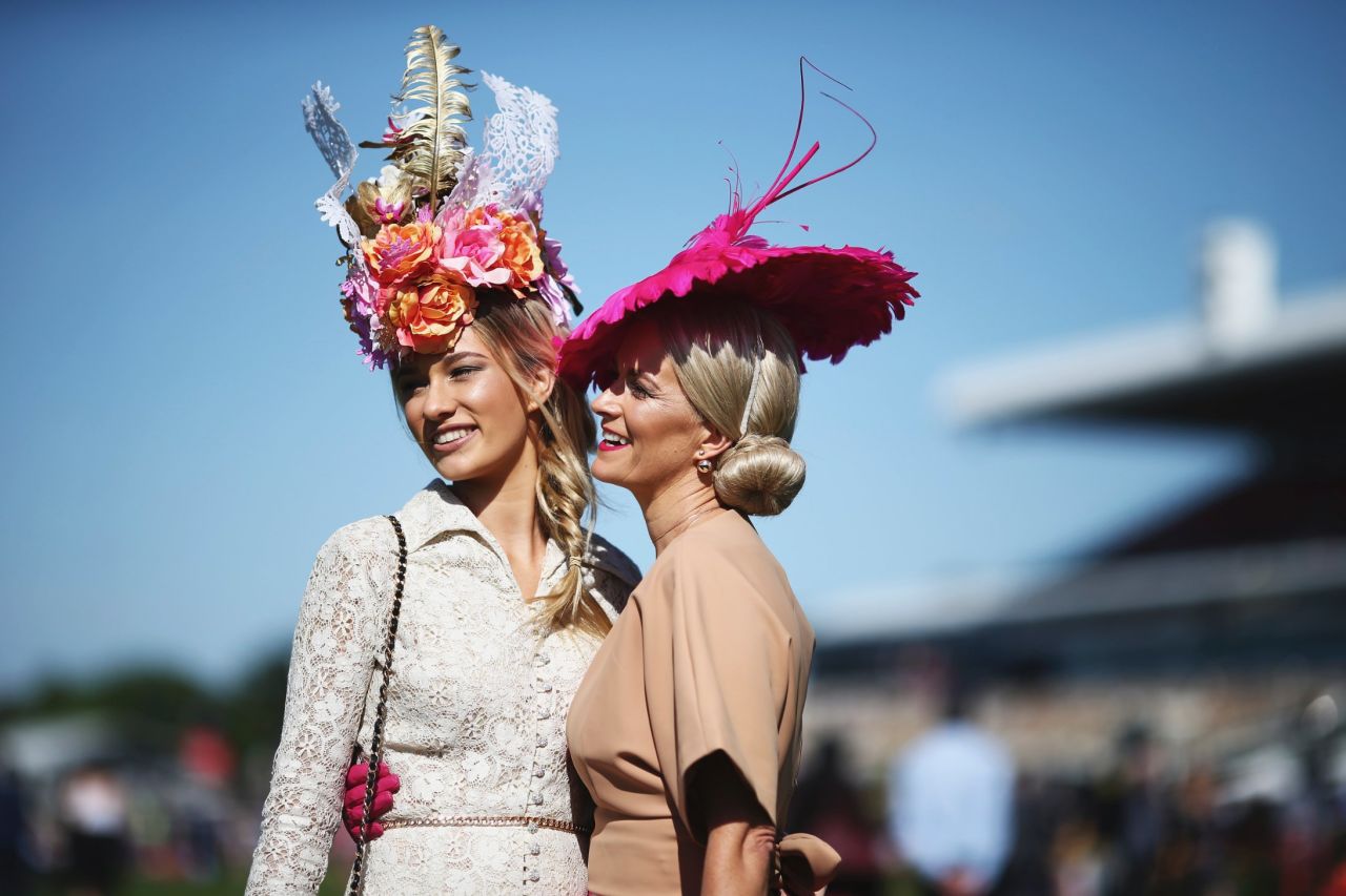 Racegoers with fashionable headpieces pose upon arrival on Melbourne Cup Day at Flemington Racecourse on November 3.