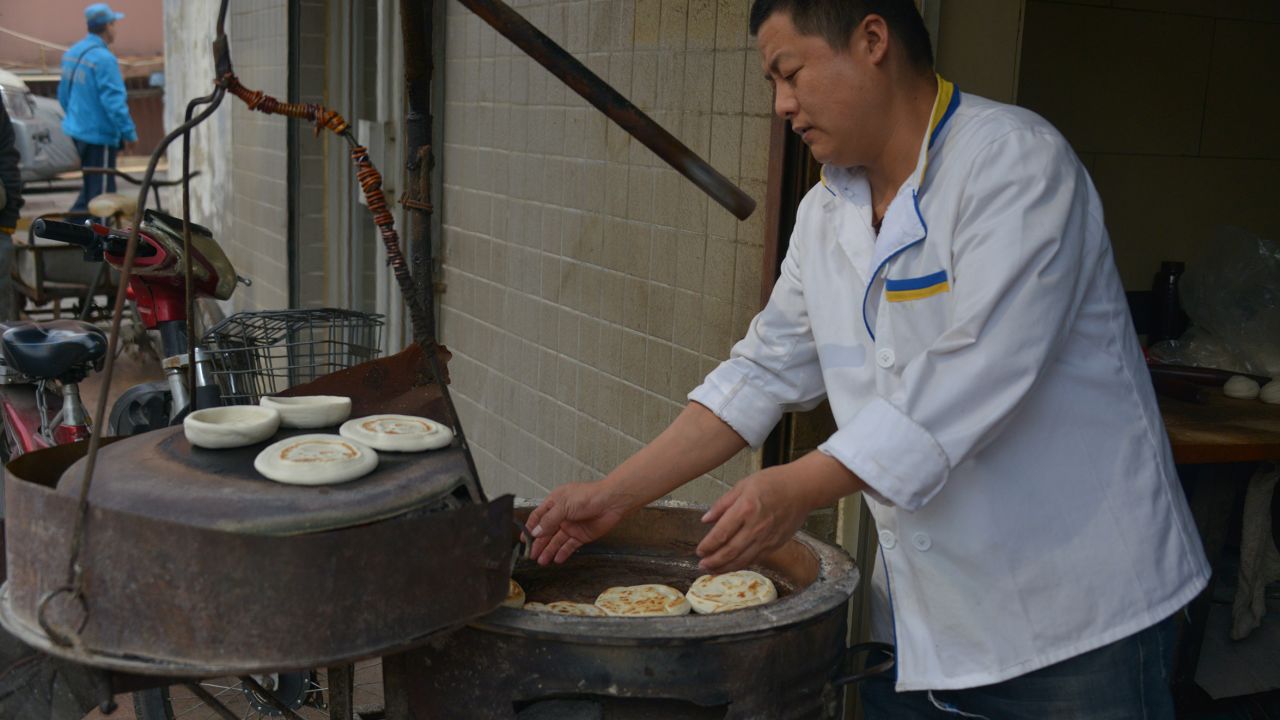 Wangkui Roujiamo restaurant's Liu Lianpeng bakes mo on a traditional furnace. 