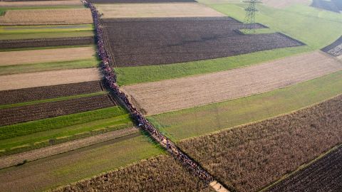 A column of migrants moves along a path between farm fields in Rigonce, Slovenia, in October 2015.