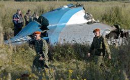 Russian soldiers walk next to the crashed airliner's fuselage the next day.