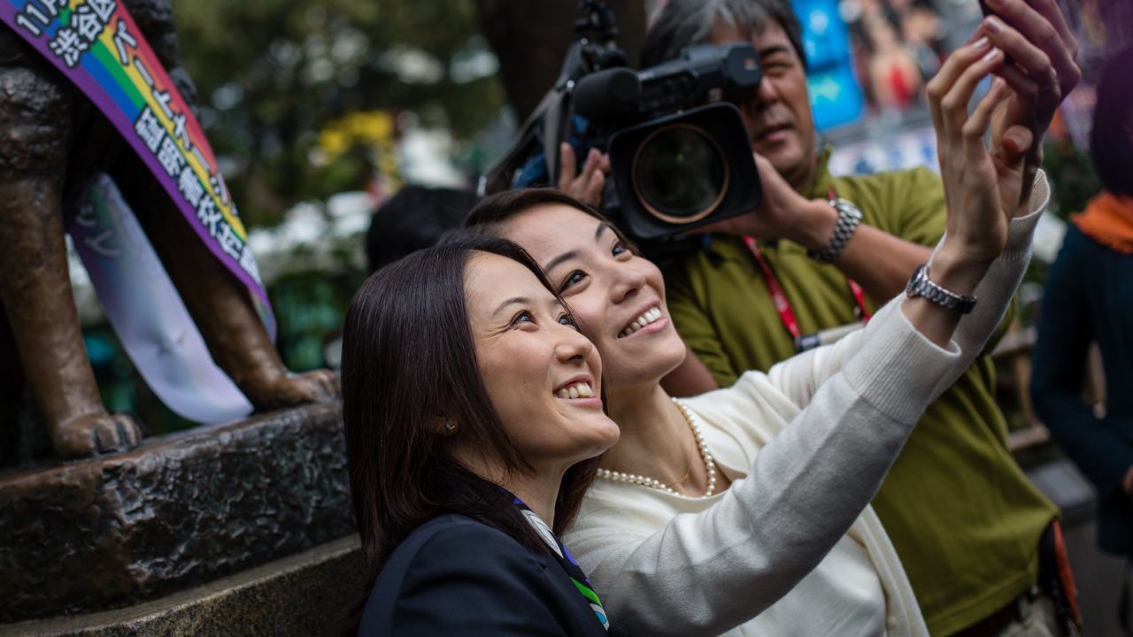 Japanese couple Hiroko Masuharda and Koyuki Higashi celebrate in front of Shibuya's Hachiko statue on November 5, 2015.