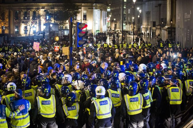 British police officers form a blockade around protesters during the Million Mask March.