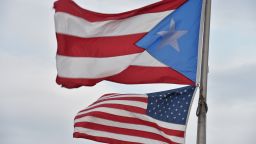 The Puerto Rican and US flags are seen in the Old Town  district  February 9, 2015  in San Juan, Puerto Rico.      AFP PHOTO/PAUL  J. RICHARDS        (Photo credit should read PAUL J. RICHARDS/AFP/Getty Images)
