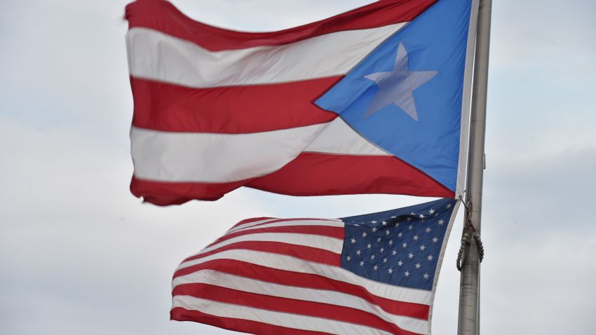 The Puerto Rican and US flags are seen in the Old Town district February 9, 2015 in San Juan, Puerto Rico. AFP PHOTO/PAUL J. RICHARDS (Photo credit should read PAUL J. RICHARDS/AFP/Getty Images)