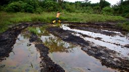 A man jumps across water contaminated by oil pollution in Ogoniland, Nigeria.  