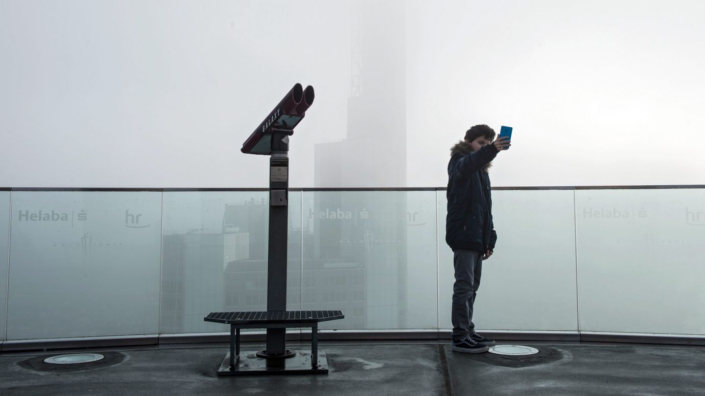 A visitor at the Main Tower skyscraper takes a selfie of the fog-covered skyline in Frankfurt am Main, Germany, on Wednesday, November 4.