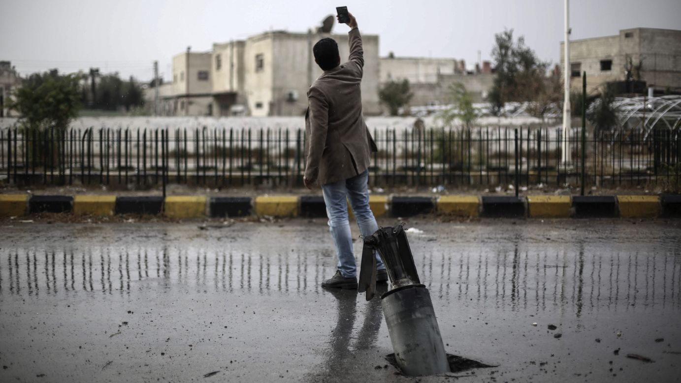 A man takes a selfie by an unexploded bomb buried in a road in Douma, Syria, on Thursday, November 5.