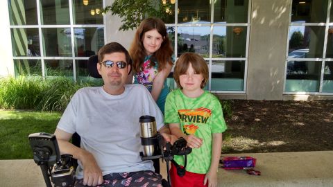 Masters sits with Sabrina and Radley in June 2015.  "The ALS Association told us you have to stay in front of this disease. Don't wait until it's an emergency," he says. "We've done some voice banking.  I'm using feet on my laptop and when they quit working I'll need the <a href="http://alsassistivetechnology.blogspot.com/2013/09/electronic-eye-gaze-communication.html" target="_blank" target="_blank">eye gaze machine </a>or <a href="http://www.controlbionics.com/" target="_blank" target="_blank">NeuroSwitch</a>. Denial is going to get you in trouble. You have to be proactive and have the next stage of tools ready when you need them."