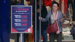 A woman walks out a shop past a "Singles Day" sales promotional board in Beijing on November 11, 2015.  Shoppers spent around 9 billion USD in the first 12 hours of China's "Singles Day" sale on November 11, e-commerce giant Alibaba said, in the world's biggest online shopping day.         AFP PHOTO / WANG ZHAO        (Photo credit should read WANG ZHAO/AFP/Getty Images)