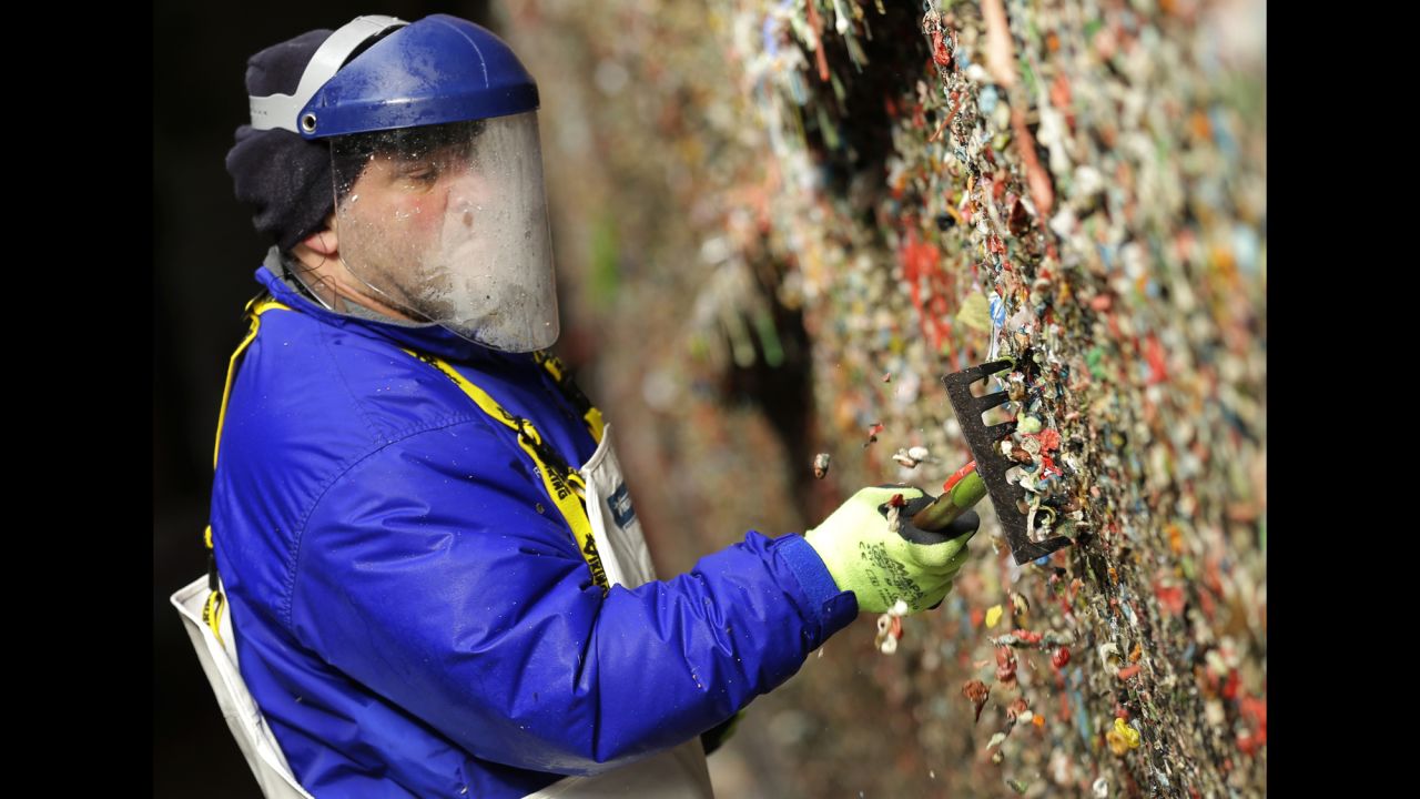 Fernando Soberania uses a tool to scrape layers of gum from the wall.