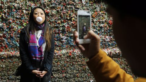 A tourist has her photo taken in front of the gum wall before the deep clean.