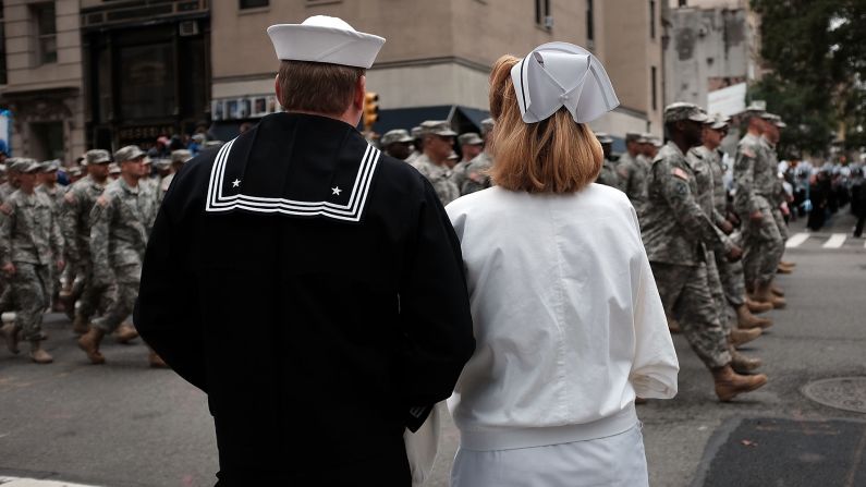 Two people dressed in classic uniforms watch the Veterans Day parade in New York City.