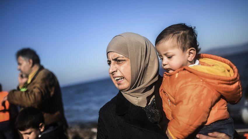 A woman holds her child as refugees and migrants get off a dinghy upon their arrival on the Greek island of Lesbos after crossing the Aegean Sea from Turkey on November 12, 2015. EU leaders attending a summit with their African counterparts approved a 1.8-billion-euro trust fund for Africa aimed at tackling the root causes of mass migration to Europe. AFP PHOTO / BULENT KILIC        (Photo credit should read BULENT KILIC/AFP/Getty Images)