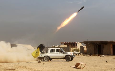 Shiite fighters, fighting alongside Iraqi government forces, fire a rocket at ISIS militants as they advance toward the center of Baiji, Iraq, on Monday, October 19.