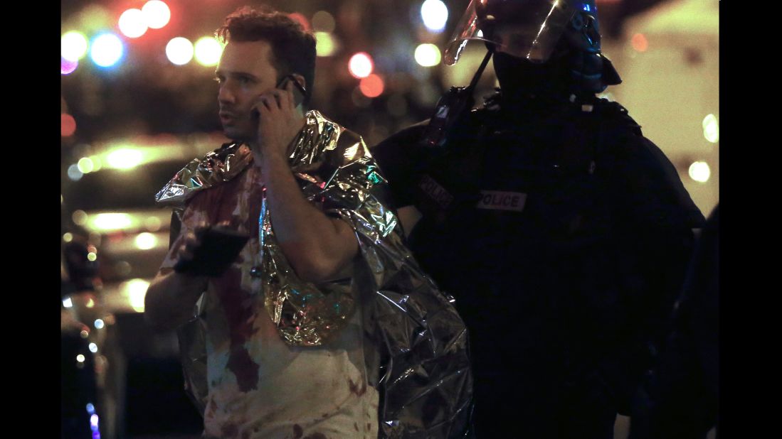 A man with blood on his shirt talks on the phone on November 14. He is next to the Bataclan theater, where gunmen shot concertgoers and held hostages until  police raided the building.