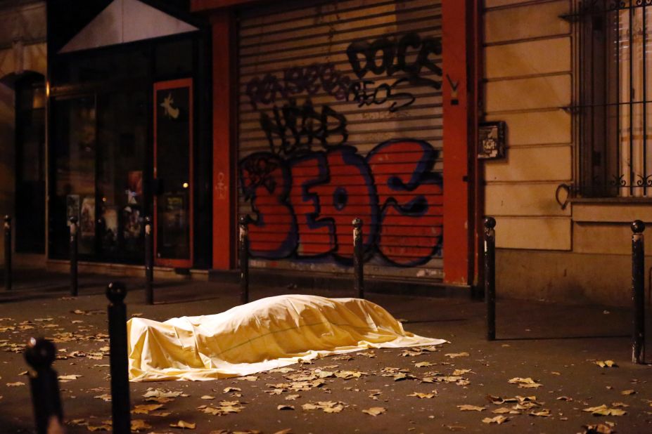 A body, covered by a sheet, is seen on the sidewalk outside the Bataclan theater.